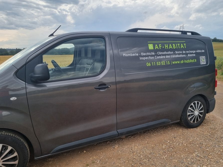 Véhicule Véhicule utilitaire gris avec un logo affichage AF-HABITAT de contact sur le côté.